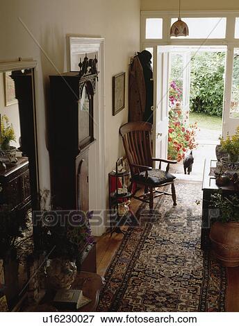 Longcase clock and patterned carpet runner in country hall with open door and view of the garden View Large Photo Image Stock Photo - Longcase clock and patterned carpet runner in country hall with open door and view of the garden. Fotosearch