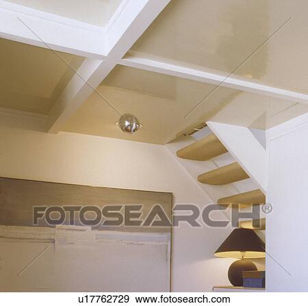 Looking up at white beams and underside of wooden staircase in white cottage hall with picture and lighted lamp View Large Photo Image Stock Photo - Looking up at white beams and underside of wooden staircase in white cottage hall with picture and lighted lamp. Fotosearch
