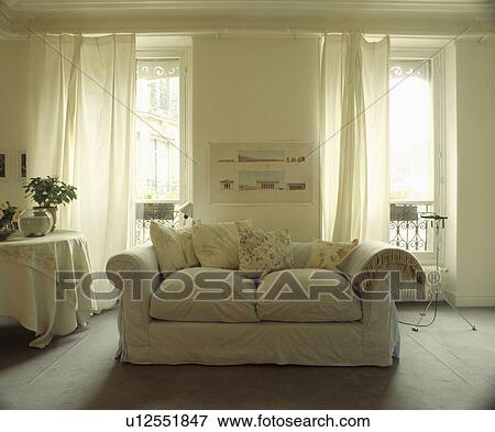 Stock Photo - Loosecover on sofa in traditional living room with white curtains. Fotosearch