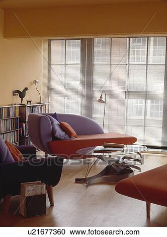 Mauve and purple modern sofa with glass and metal table in loft conversion living room with Venetian blind at the window View Large Photo Image Stock Image - Mauve and purple modern sofa with glass and metal table in loft conversion living room with Venetian blind at the window. Fotosearch