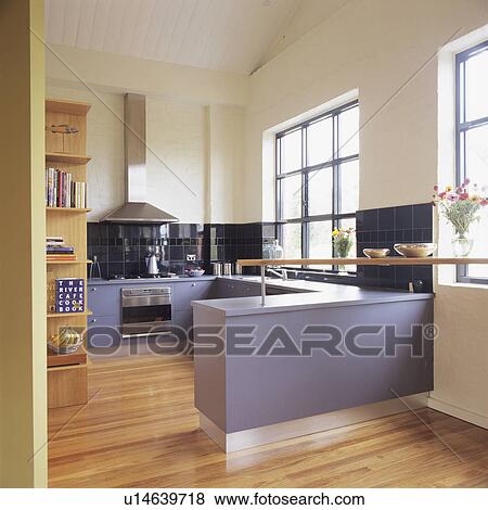 Stock Photo - Mauve fitted cupboards in modern white kitchen with wooden flooring. Fotosearch