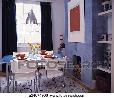 Metal and white palstic chairs and blue table in blue dining room with abstract picture on fireplace wall View Large Photo Image Stock Photograph - Metal and white palstic chairs and blue table in blue dining room with abstract picture on fireplace wall. Fotosearch