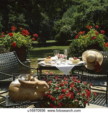Stock Photograph - Metal chairs on patio in large country garden in summer. Fotosearch
