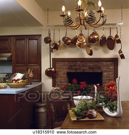 Metal ferns on lighted chandelier above table in kitchen dining room with copper pans above fireplace View Large Photo Image Stock Image - Metal ferns on lighted chandelier above table in kitchen dining room with copper pans above fireplace. Fotosearch