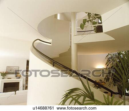 Metal handrail on curved bannister wall of modern staircase in white hall with green houseplants View Large Photo Image Stock Image - Metal handrail on curved bannister wall of modern staircase in white hall with green houseplants . Fotosearch
