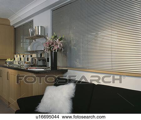 Picture - Metal slatted blind above black sota with white cushion in modern kitchen. Fotosearch