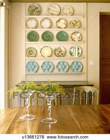 Stock Photo - Mimosa in stemmed glasses on table in dining room with antique green and turquoise plates on white shelves. Fotosearch