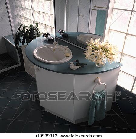 Stock Photo - Mirror above circular basin set into curved white vanity unit with turquoise top. Fotosearch