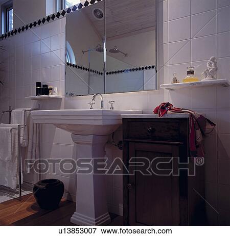 Stock Photo - Mirror above white pedestal basin and small marble-topped antique cupboard. Fotosearch