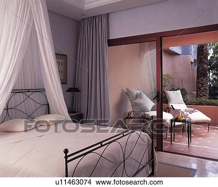 Picture - Modern bedroom leading onto terrace with sunloungers.. Fotosearch