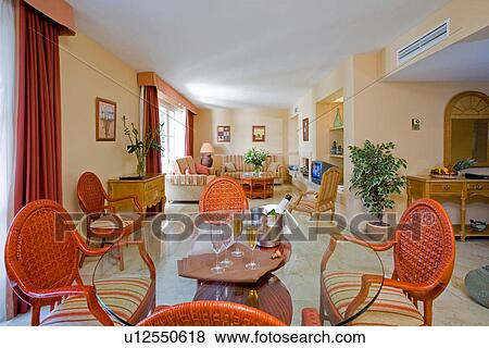 Stock Photo - Modern hotel lounge with orange curtains and chairs around circular glass table with glasses and bottle of wine in ice bucket. Fotosearch