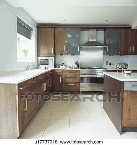 Stock Photo - Modern kitchen with white tiled floor and dark wood units. Fotosearch