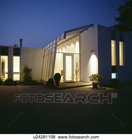 Stock Photo - Modern white house in the country lit at night. Fotosearch