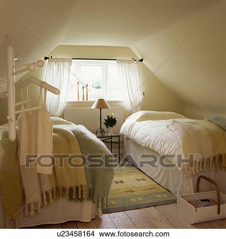 Mohair blankets and cream linen on twin beds in attic guest bedroom with patterned yellow rug on wooden flooring View Large Photo Image Picture - Mohair blankets and cream linen on twin beds in attic guest bedroom with patterned yellow rug on wooden flooring. Fotosearch