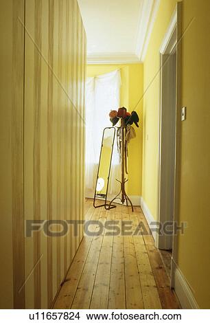 Narrow yellow hall corridor with wooden flooring and long mirror View Large Photo Image Picture - Narrow yellow hall corridor with wooden flooring and long mirror. Fotosearch
