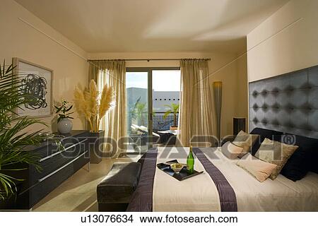 Neutral Bedroom With Black Furniture And Cream Curtains At Patio