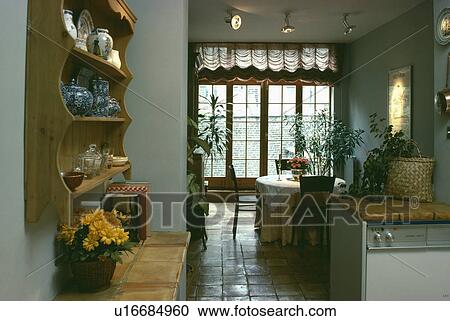 Stock Image - Old pine shelves above tiled worktop in traditional kitchen dining room with terracotta tiled floor. Fotosearch