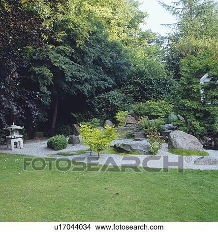 Picture - Oriental rock garden with raked gravel in front of tall trees including a copper beech. Fotosearch
