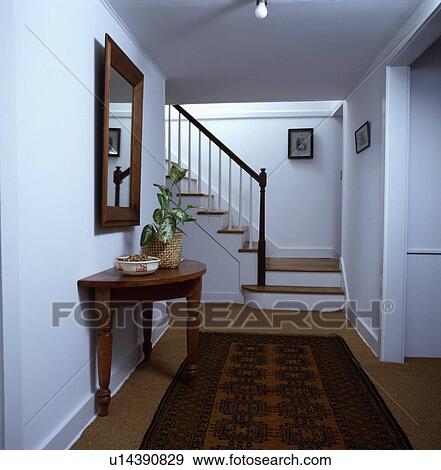 Stock Photo - Oriental rug on sisal carpet in white hall with antique console table . Fotosearch