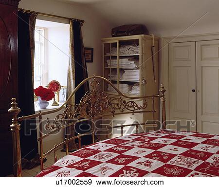 Ornate antique brass bed with red+white checked duvet in small country bedroom View Large Photo Image Stock Photo - Ornate antique brass bed with red+white checked duvet in small country bedroom. Fotosearch