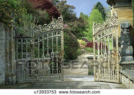 Stock Image - Ornate metal gates and view of large country garden. Fotosearch