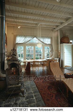 Stock Image - Ornate stove and chaiselongue in traditional openplan living and dining room. Fotosearch