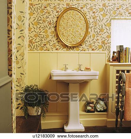 Oval mirror above white pedestal basin in traditional bathroom with yellow panelling below lemon-patterned wallpaper View Large Photo Image Stock Photo - Oval mirror above white pedestal basin in traditional bathroom with yellow panelling below lemon-patterned wallpaper. Fotosearch
