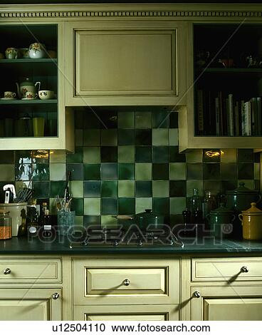 Stock Image - Pale and dark green tiles above kitchen hob. Fotosearch