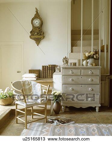 Pale wood chest of drawers and small chair in cream hall with antique wall clock View Large Photo Image Stock Image - Pale wood chest of drawers and small chair in cream hall with antique wall clock. Fotosearch