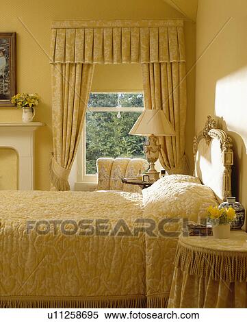 Pale Yellow Damask Curtains At Window And Matching Quilt On Bed In Yellow Traditional Bedroom Stock Photography