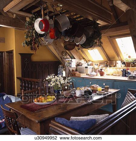 Pans on metal rack above rectangular wooden table and bench in yellow attic kitchen View Large Photo Image Stock Image - Pans on metal rack above rectangular wooden table and bench in yellow attic kitchen. Fotosearch