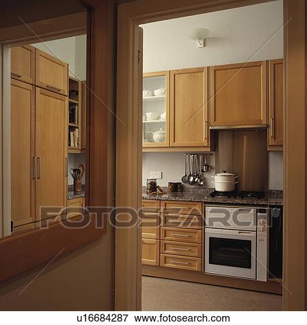 Stock Photo - Pans on white oven in modern pale wood fitted kitchen. Fotosearch