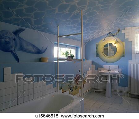 Stock Photography - Pastel blue sea themed bathroom with painted ceiling and fish mural and lifebuoy lighting above pedestal basin . Fotosearch