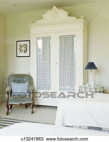 Pastel blue velvet Victorian chair beside painted white glass-fronted cupboard with checked drapes View Large Photo Image Stock Image - Pastel blue velvet Victorian chair beside painted white glass-fronted cupboard with checked drapes. Fotosearch