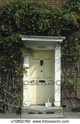 Stock Image - Pastel yellow front door with white frame. Fotosearch