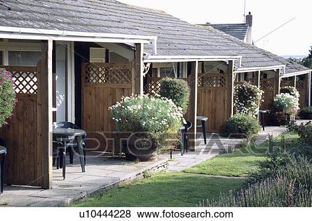 Stock Photo - Patios and flowering plants in pots in front of ground floor rooms in country hotel in summer. Fotosearch