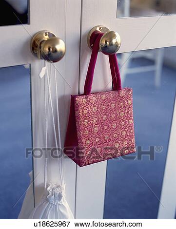 Stock Photo - Pattered red silk evening bag on brass door knob. Fotosearch