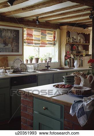 Stock Image - Patterned blind above sink in beamed cottage kitchen. Fotosearch