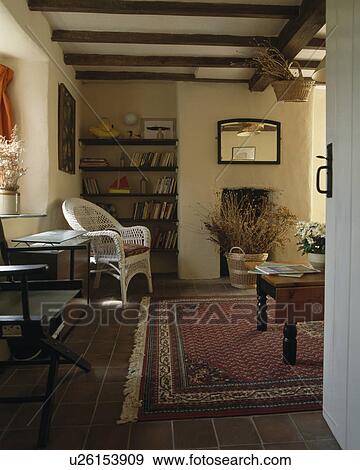 Patterned red oriental carpet in cottage livingroom with dried flowers in fireplace and white wicker chair in front of bookshelves View Large Photo Image Stock Photo - Patterned red oriental carpet in cottage livingroom with dried flowers in fireplace and white wicker chair in front of bookshelves. Fotosearch