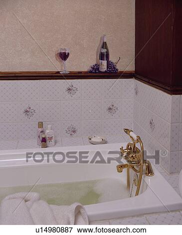 Stock Photo - patterned wall tiles and brass taps on bath full of water . Fotosearch