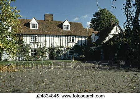 Stock Photography - Paved area in front of black and white timbered cottage . Fotosearch
