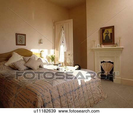Peach+blue quilt on bed in peach bedroom with small cream fireplace View Large Photo Image Stock Photo - Peach+blue quilt on bed in peach bedroom with small cream fireplace. Fotosearch