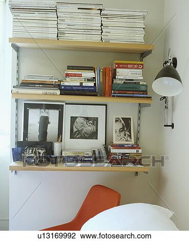 Photographs with magazines and books on shelves beside modern wall-lamps View Large Photo Image Stock Image - Photographs with magazines and books on shelves beside modern wall-lamps. Fotosearch