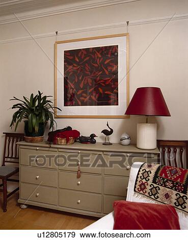 Stock Photo - Picture above red lamp and green houseplant on dark beige chest-of-drawers. Fotosearch