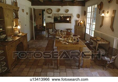 Stock Photograph - Pine table and chairs in country dining room with pine dresser and terracotta tiled floor. Fotosearch