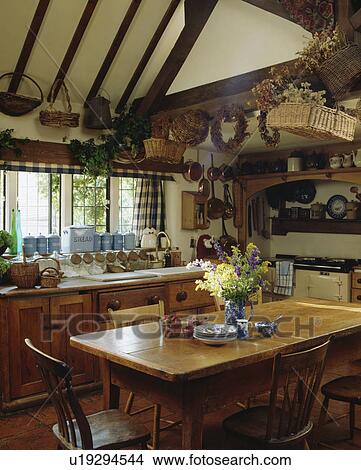 Picture - Pine table and old chairs in country kitchen with baskets on ceiling. Fotosearch