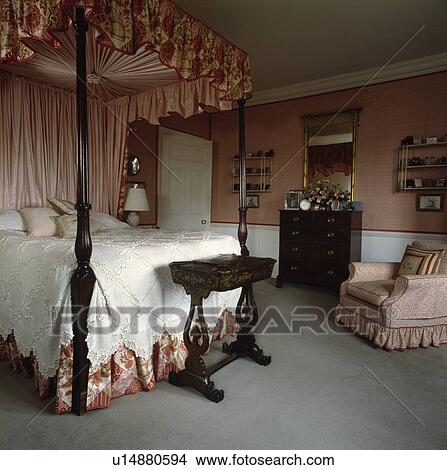 Pink silk drapes and lace bedcover on fourposter bed in pink country bedroom with grey carpet and antique furniture View Large Photo Image Picture - Pink silk drapes and lace bedcover on fourposter bed in pink country bedroom with grey carpet and antique furniture. Fotosearch