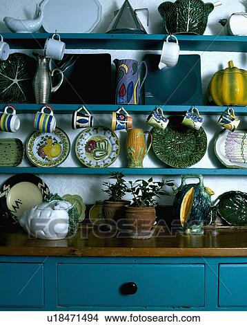 Pottery cups and plates on blue shelves above dresser with wooden top and blue base View Large Photo Image Picture - Pottery cups and plates on blue shelves above dresser with wooden top and blue base. Fotosearch
