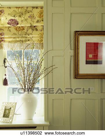 Stock Image - Pussy-willow branches in vase in front of window with floral blind. Fotosearch