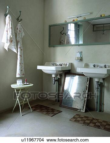 Rectangular mirror above double white basins in traditional bathroom with small metal table and old silvered mirror View Large Photo Image Picture - Rectangular mirror above double white basins in traditional bathroom with small metal table and old silvered mirror. Fotosearch